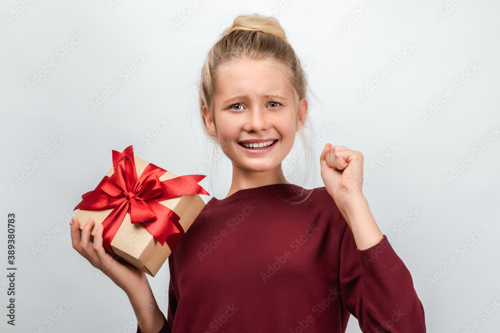 Portrait of happy blonde girl holding gift decorated with ribbon. Studio shot white background Portrait of happy blonde girl holding gift decorated with ribbon. Studio shot white background