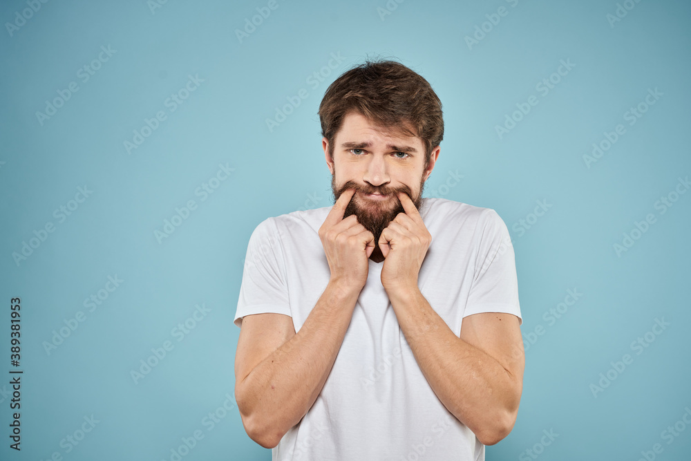 Man in white t-shirt lifestyle studio emotions facial expression blue isolated background Man in white t-shirt lifestyle studio emotions facial expression blue isolated background