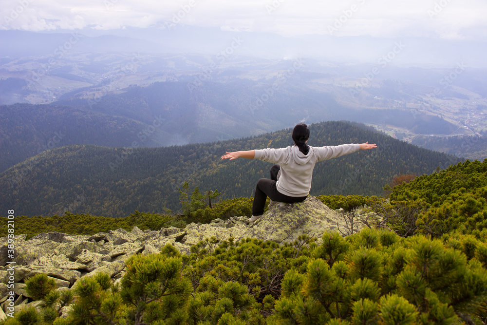 Happy woman with hands up on the peak of the mountain .Tourism, travel, climbing, hiking, active leisure concept