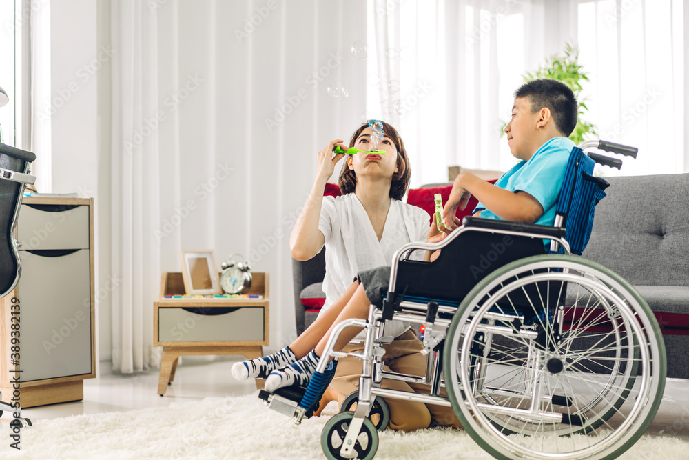 Portrait of enjoy happy love family asian mother playing and carer helping look at disabled son child sitting in wheelchair moments good time at home.disability care concept Portrait of enjoy happy love family asian mother playing and carer helping look at disabled son child sitting in wheelchair moments good time at home.disability care concept