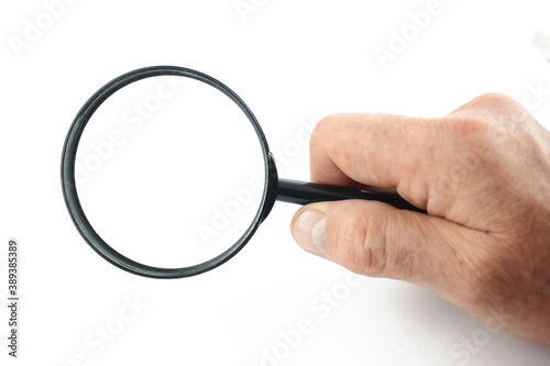 Hand holds magnifying glass isolated on white background.