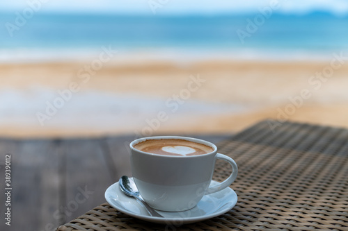 Latte art coffee cup on table near beach