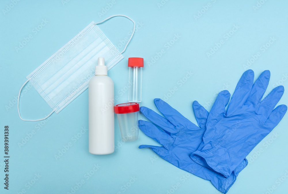 Medical mask to protect against corona virus. On a blue background. Gloves. Analysis container. Close-up. Disinfection bottle.