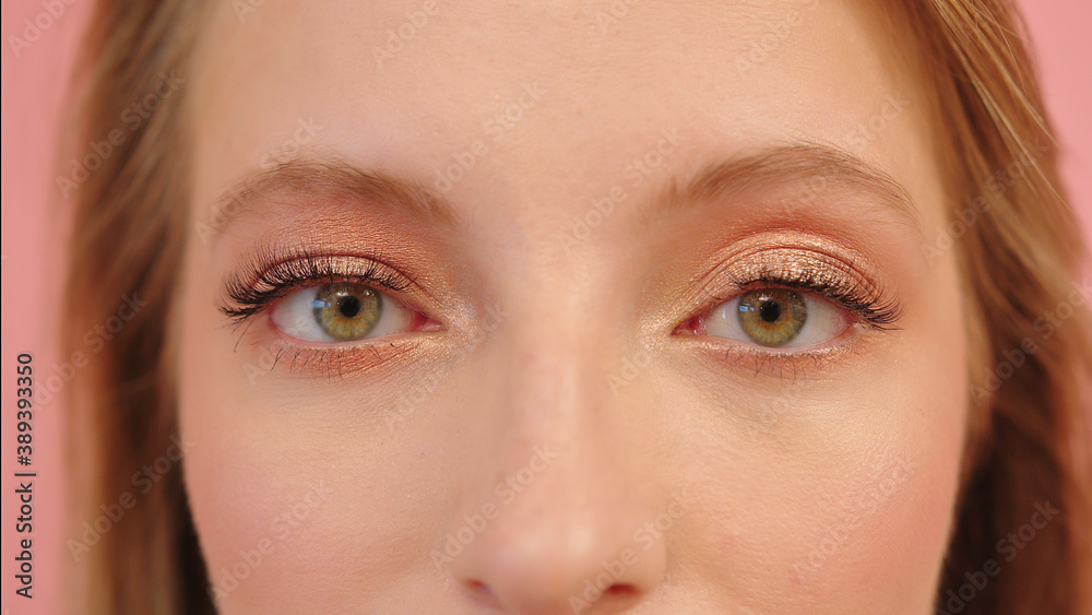 Fototapeta premium Big green eyes of young caucasian smiling woman, close up, studio shot. High quality photo