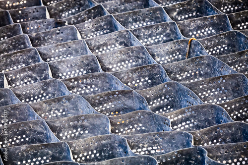 Cellular confinement system - plastic black honeycomb frame filled with small natural stones closeup. Used in construction for erosion control, soil stabilization on flat ground and steep slopes photo