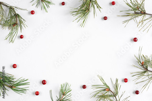 Christmas background with cranberries and pine branches on a white backdrop. Top view, flat lay, copy space