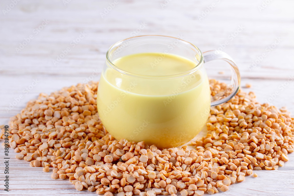 Vegetable pea milk in glass and peas on the table. Nut free, soy free, lactose free, gluten free concept Vegetable pea milk in glass and peas on the table. Nut free, soy free, lactose free, gluten free concept