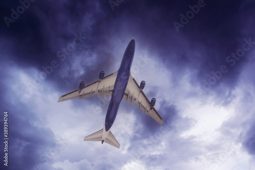 The plane flies through the cloudy sky, bottom view