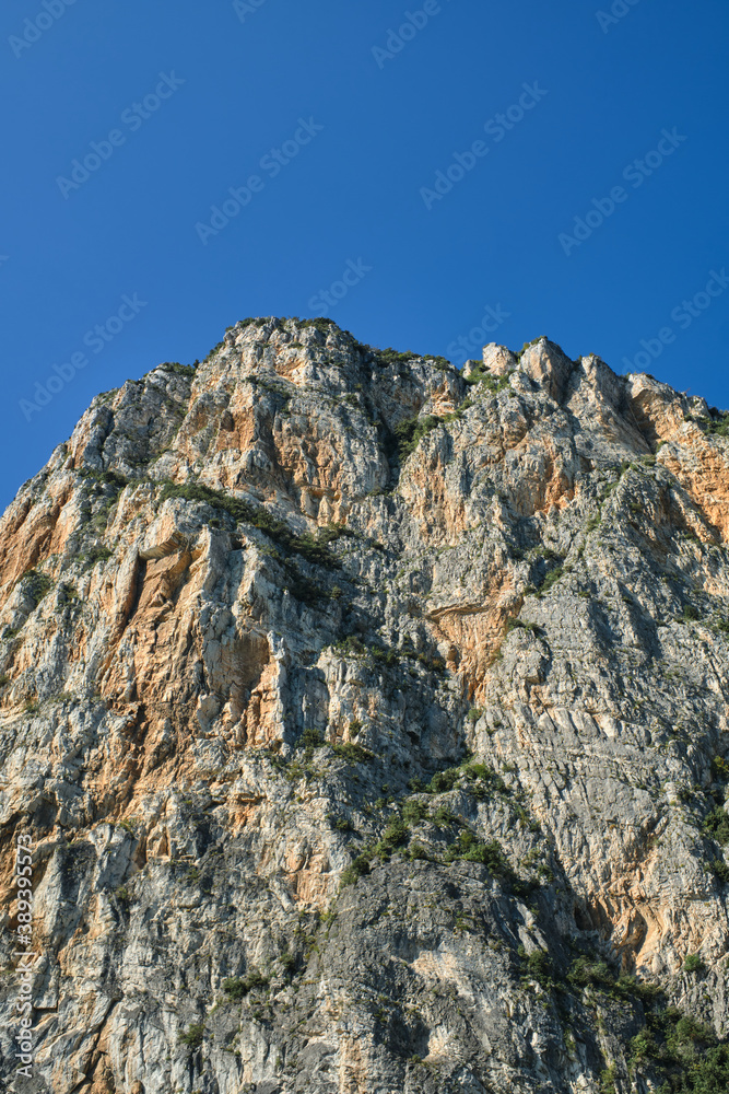 Alps top on blue sky. Rough rocky stones. The tops of the yellow peaks of the rocks. Red stones on a blue background. Gray rocks at high altitude.