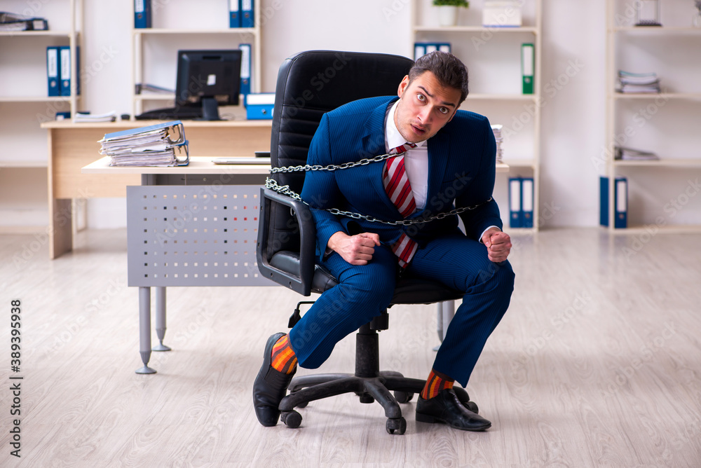 Chained male employee working in the office Chained male employee working in the office
