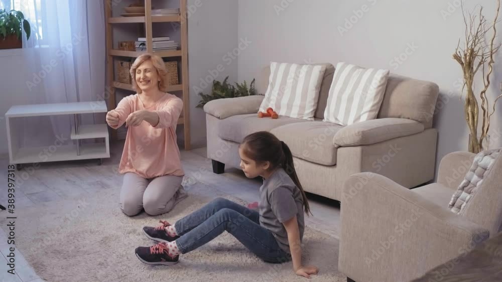 Grandmother and granddaughter do joint hand gymnastics. They sit on carpet in room. Caucasian girl of 10 makes bend crab. High quality 4k footage Grandmother and granddaughter do joint hand gymnastics. They sit on carpet in room. Caucasian girl of 10 makes bend crab. High quality 4k footage