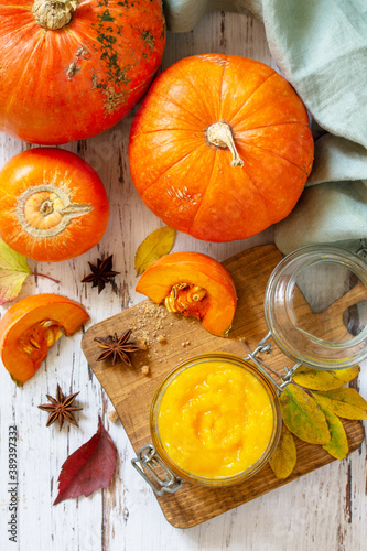 Pumpkin Puree with spices and Pumpkin on a wooden table. Top view flat lay background.