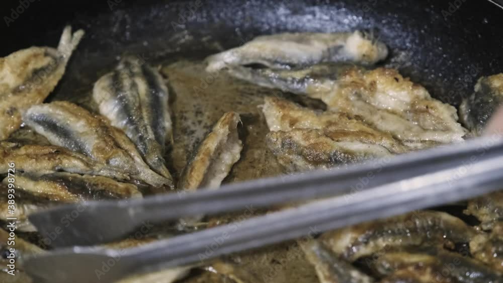 Fried anchovies in a pan. Cooking anchovies. Small fish fry in the pan. Cooking anchovies in oil
