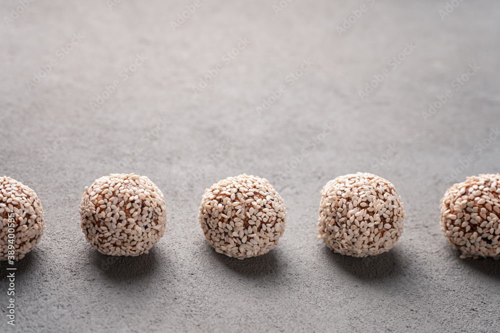 Date candies with sesame seeds on a concrete table are laid out in a row close-up Date candies with sesame seeds on a concrete table are laid out in a row close-up