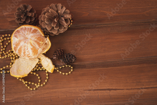 Christmas wooden background, pine cones gold beads open mandarin. Christmas red background