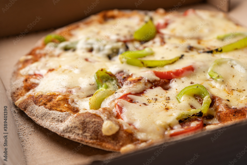 Vegetarian pizza with paprika on wholegrain dough in a cardboard box for delivery
