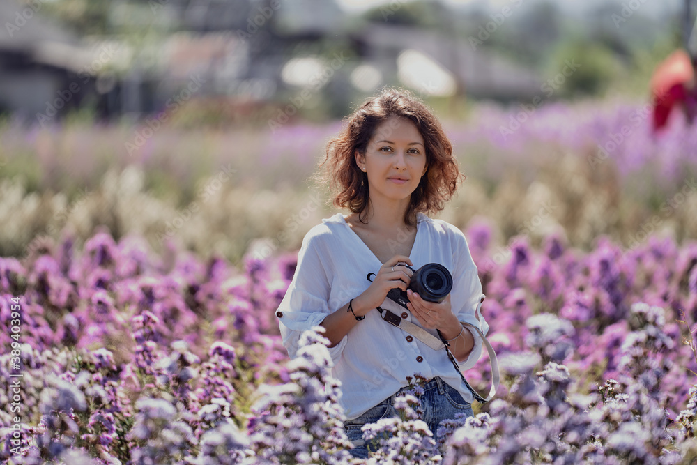 young cute woman professional photographer on a flower field in summer