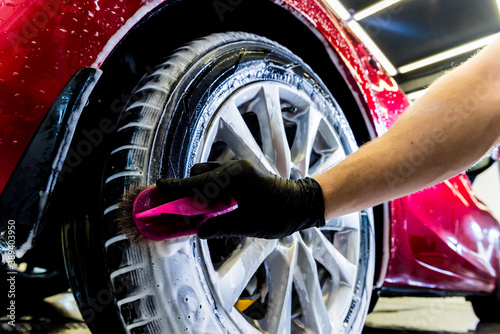 Cleaning the car wheel with a brush and water photo