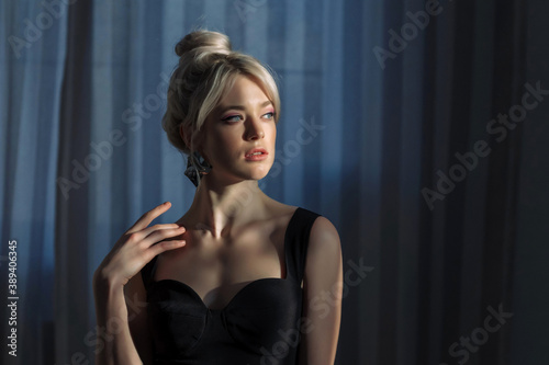 Close up studio portrait of a pretty blonde woman in black top.