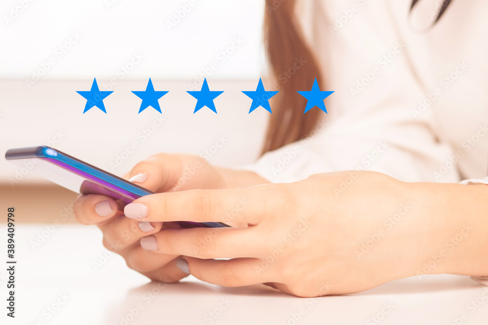 Woman hand using smart phone with icon five star symbol to increase rating of company concept Woman hand using smart phone with icon five star symbol to increase rating of company concept
