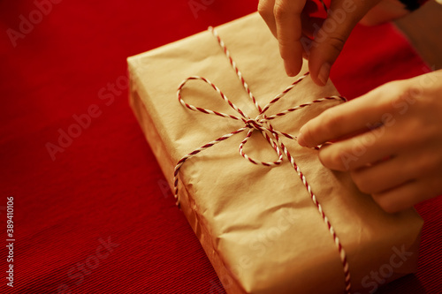 Women's hands tie a ribbon on a gift on a red background