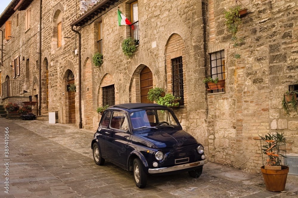 An alley of an Italian medieval village with an old car parked (Gubbio, Umbria, Italy)