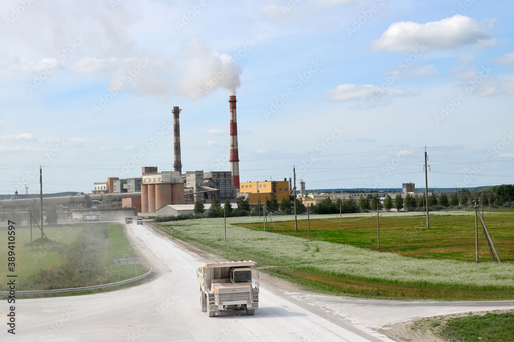 Big yellow dump truck on the background of an industrial cement factory. Concrete factory. Loading and transportation of minerals in the chalk mining quarry, Belarus, Krasnoselsk Big yellow dump truck on the background of an industrial cement factory. Concrete factory. Loading and transportation of minerals in the chalk mining quarry, Belarus, Krasnoselsk