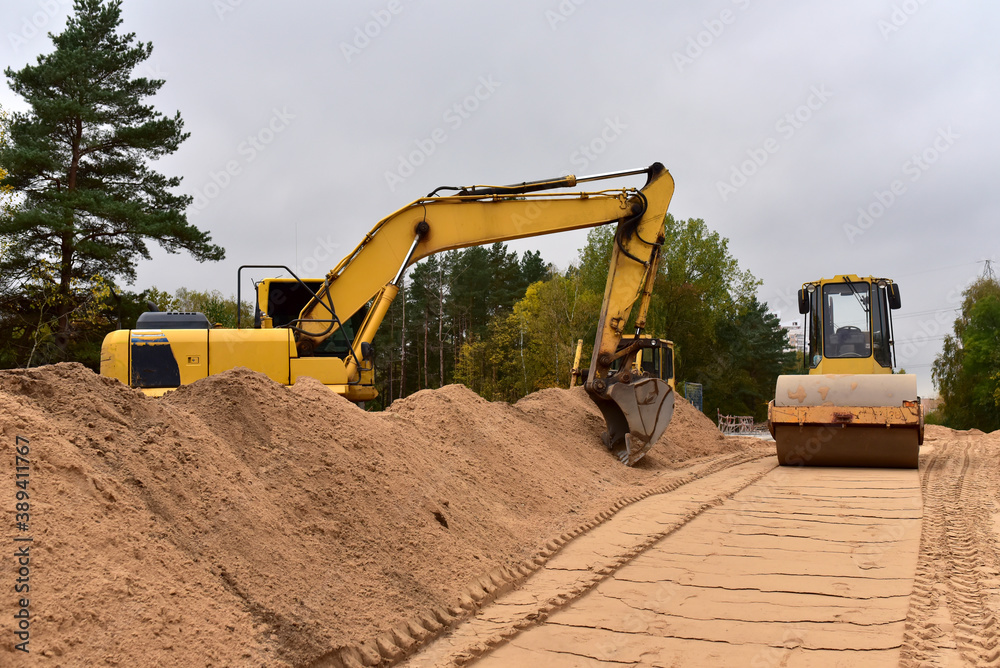 Excavator and Vibro Roller Soil Compactor at road construction and bridge projects in forest area. Heavy machinery for road work. Building a road works. Leveling and compaction of ground Excavator and Vibro Roller Soil Compactor at road construction and bridge projects in forest area. Heavy machinery for road work. Building a road works. Leveling and compaction of ground