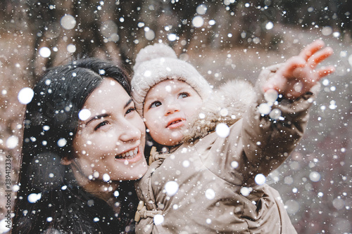 Beautiful young mom and her little cute daughter have fun outdoors in winter. Happiness to spend time together. Family concept.