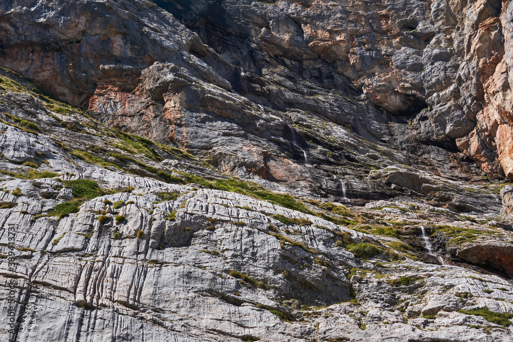 sheer rock wall with a small waterfall flowing down it sheer rock wall with a small waterfall flowing down it