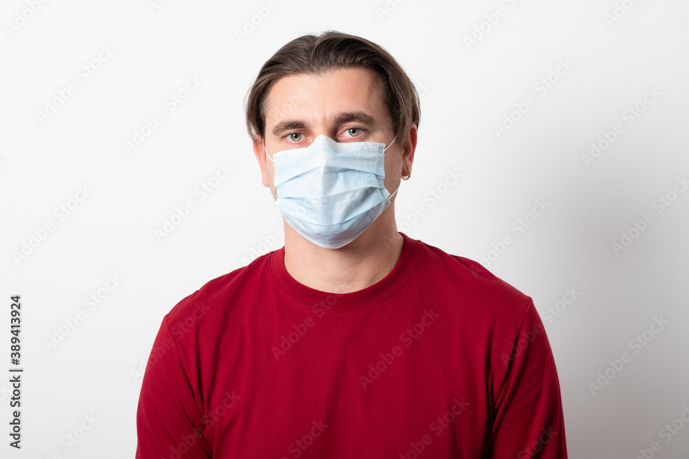 Man wearing a surgical mask during a pandemic. Studio image of a young man in a medical mask. Man wearing a surgical mask during a pandemic. Studio image of a young man in a medical mask.