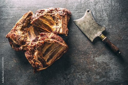 Top view of smoked ribs on a dark metallic surface next to a vintage knife photo