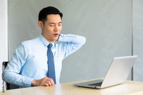 young asian businessman getting neck pain after working with computer for long period. office syndrome concept