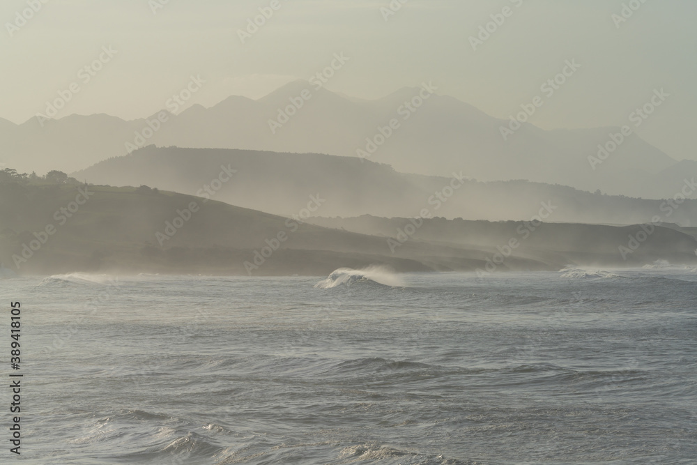 mountain landscape in silhouette with beach and waves breaking in the foreground