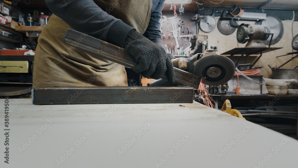 A man in gloves cuts metal with a circular saw, a lot of sparks. The working process