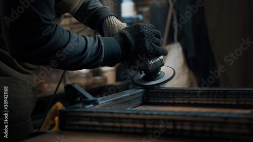 A man in gloves cuts metal with a circular saw, a lot of sparks. The working process