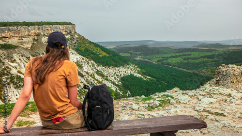 Foto A girl tourist sits on a wooden bench on the top of the Crimean mountains, which offers a beautiful view