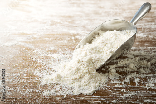 Flour and scoop on floured wooden pastry board, space for text, selective focus. photo