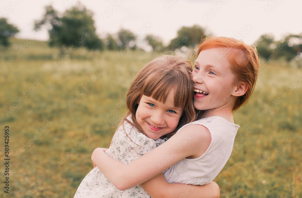 two little girls sisters play and have fun on the grass holding hands in light dresses.Summer, Sunny weather in a good mood two little girls sisters play and have fun on the grass holding hands in light dresses.Summer, Sunny weather in a good mood