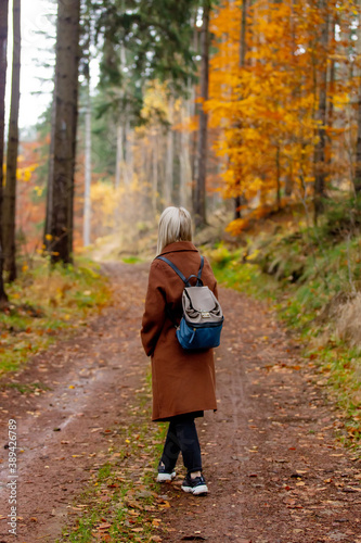woman in cloak and backpack is walks through the woods in autumn © Masson