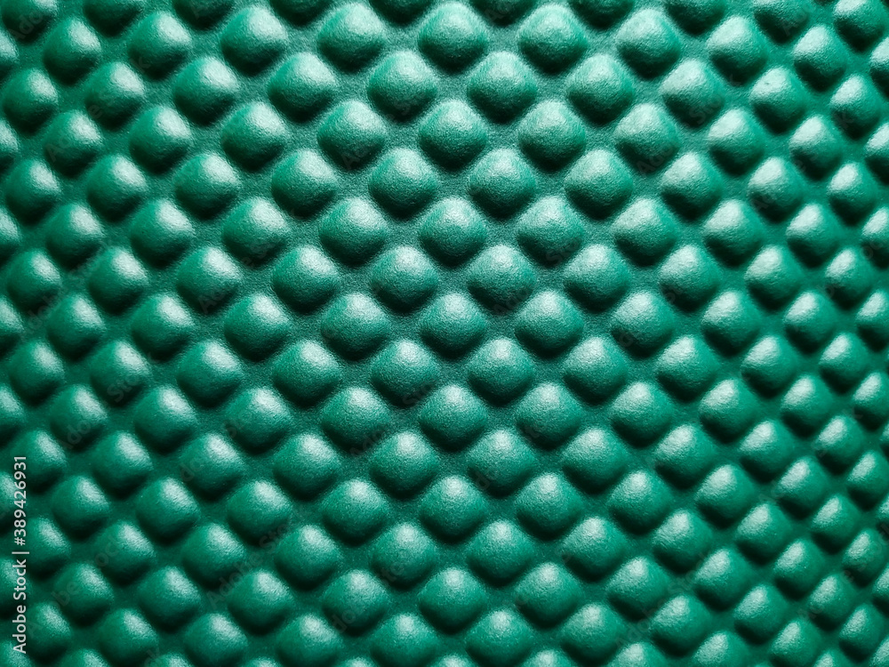 Green rubber mat texture closeup inside a gym. Top view of fitness floor background with copy space.