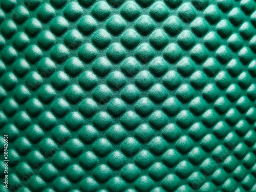Green rubber mat texture closeup inside a gym. Top view of fitness floor background with copy space.