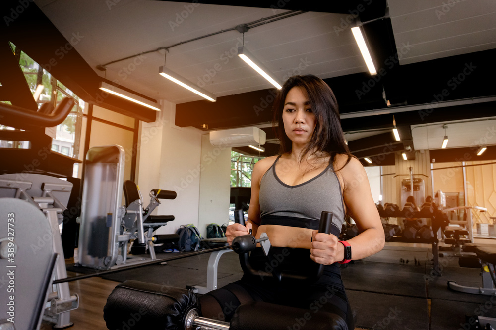 Young beautiful woman in sportswear working out with machine in gym Young beautiful woman in sportswear working out with machine in gym