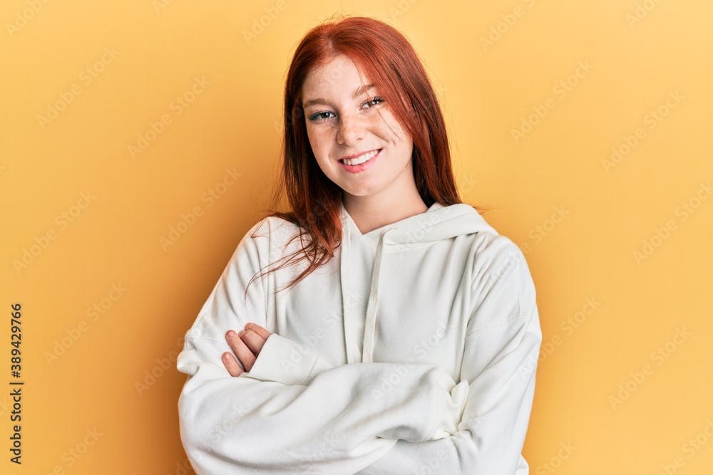 Young red head girl wearing casual sweatshirt happy face smiling with crossed arms looking at the camera. positive person. Young red head girl wearing casual sweatshirt happy face smiling with crossed arms looking at the camera. positive person.