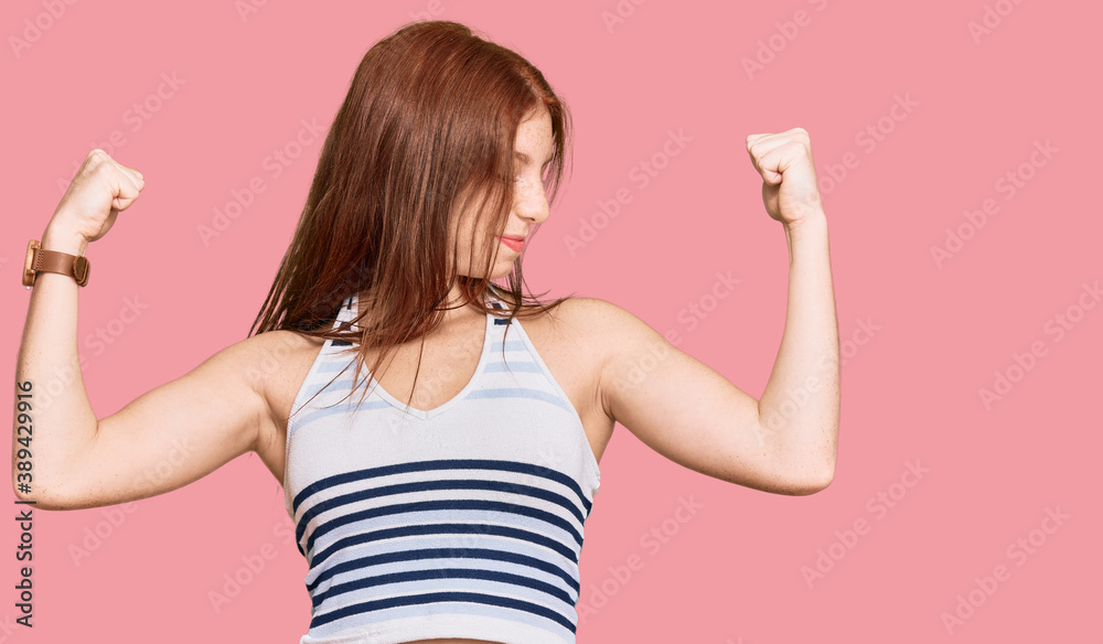 Young read head woman wearing casual clothes showing arms muscles smiling proud. fitness concept. Young read head woman wearing casual clothes showing arms muscles smiling proud. fitness concept.