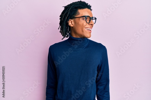 Young african american man wearing turtleneck sweater and glasses looking to side, relax profile pose with natural face and confident smile.