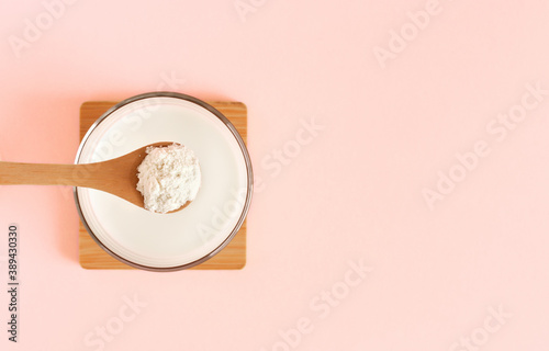 A spoon with collagen and almond or coconut milk on a pink background. Healthy lifestyle