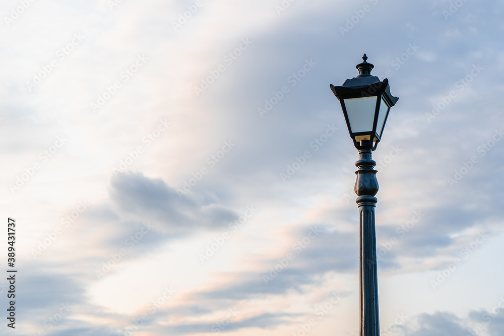 Street light with classic lamppost against a cloudy sky. Vintage style lamp post outdoors with copy space