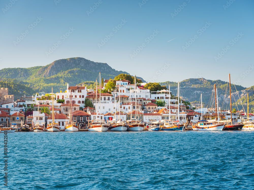 view from boat to the city with yachts and mountains on horizon under blue sky in Turkey 