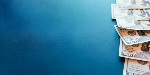 American cash dollars. Hundred-dollar bills in hand on blue background. Copy space for text.